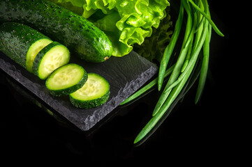 Set for cooking salad with herbs, cucumbers and onions on a black background