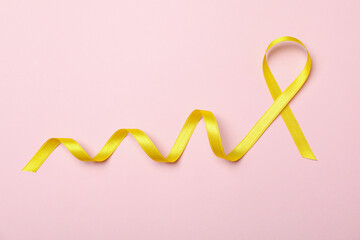 Obraz na płótnie Canvas Yellow awareness ribbon on pink background, space for text