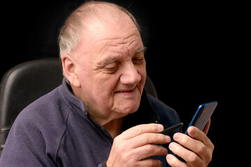portrait vieil homme utilisant son smartphone fond noir