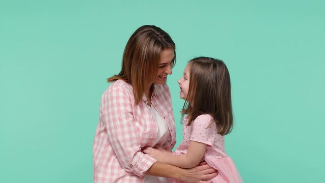 Woman in pink clothes have fun with cute child baby girl 5-6 years old. Mommy tickle little kid daughter rejoice joy gladden isolated on pastel blue background studio. Mother's Day love family concept