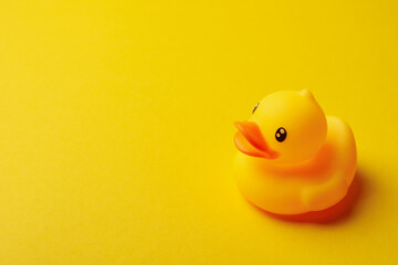 Rubber duck on yellow background, space for text