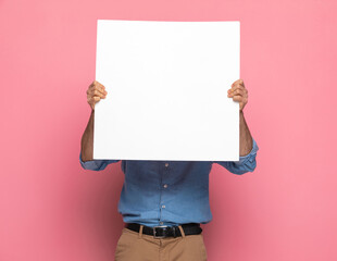 portrait of casual guy covering face with empty white board