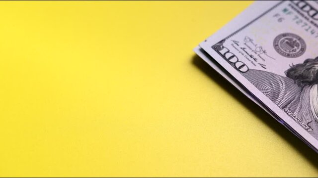 Shrinking stack of one-hundred-dollar fiat money on yellow surface. Space for text. Concept of losses, unsuccessful investment. Stop motion shooting