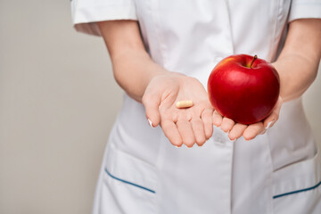 nutritionist doctor healthy lifestyle concept - holding organic red apple and vitamin or medicine...