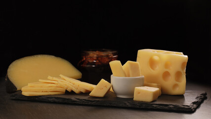 different types of cheese cut into slices lie on stone plate with honey and walnut