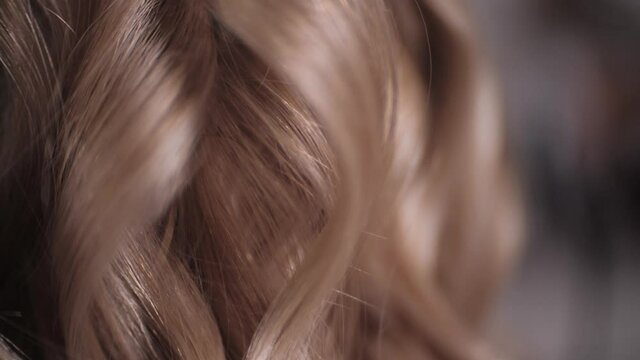 Very close-up, as the master puts the curled strands of hair to the blonde. High quality 4k footage