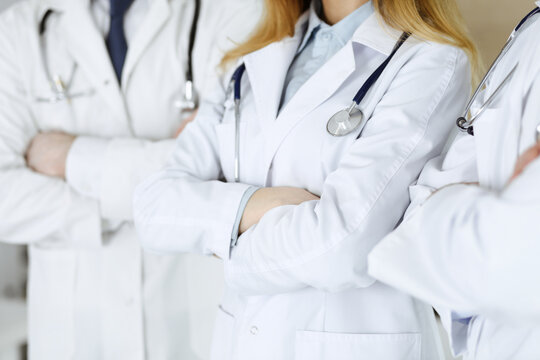 Group of unknown doctors standing as a team with arms crossed in hospital office, close-up. Medical help, insurance in health care and medicine concept