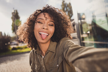 Photo of wavy hairdo funny carefree dark skin person make selfie show tongue out have good mood...
