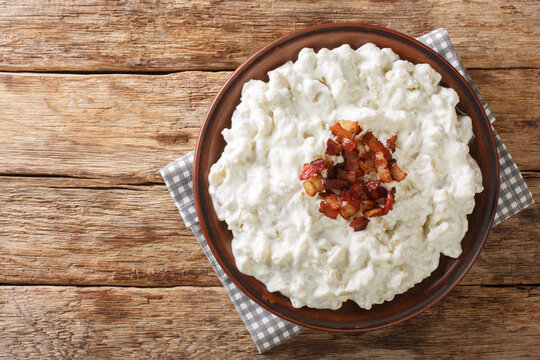 Bryndzove halusky or sheep cheese dumplings are a Slovak national dish prepared from potatoes, sheep cheese and bacon closeup on the table. Horizontal top view from above