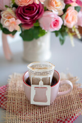 Coffee Break Time. Vertical image of A cup of Drift coffee, and Rose Flower vase place on white home office.