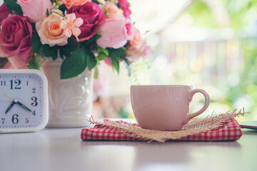Coffee Break Time. A cup of coffee, Rose Flower vase, and clock place on white home office.