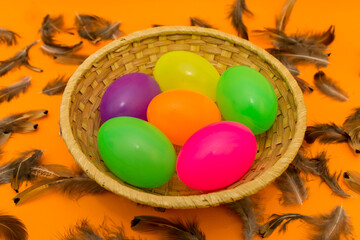 Fototapeta na wymiar Wicker basket with colorful Easter eggs on yellow background.