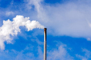 One Industrial smoke pipe from chimney on blue cloudy sky.