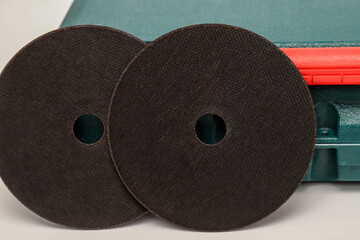 Abrasive black wheel, grinding wheel on the background of the green toolbox. Abrasive materials, discs, tools