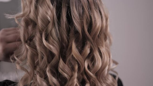 The blonde straightens her hair with her hands, showing off her hairstyle-styled curled curls. High quality 4k footage