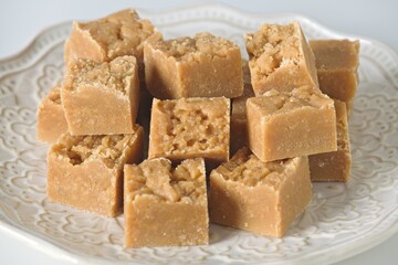 Homemade fudge cut into cubes on plate on white kitchen counter