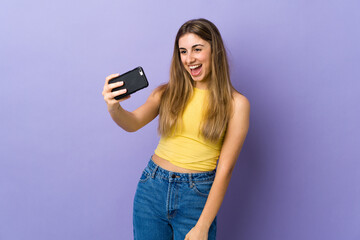 Young woman over isolated purple background making a selfie