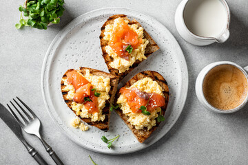 scrambled eggs toast with salmon and microgreens on a white ceramic plate, selective focus, view from above