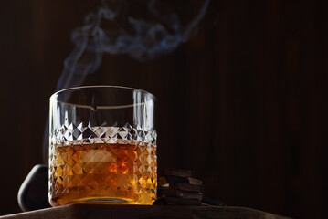 Glass of whiskey with chocolate and tobacco pipe in a smoke bar.