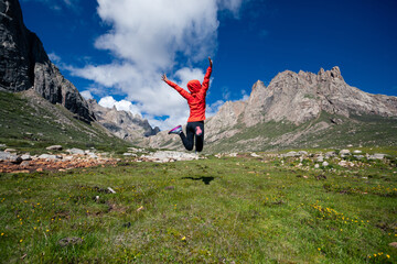 Woman trail runner jumping in wild mountains