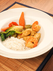 Red Thai curry with chicken and shrimps with fried vegetables and rice
