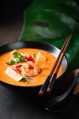 Tom Yam kung Spicy Thai soup with shrimp in a black bowl on a dark background, selective focus