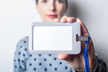 Young woman holding badge, name tag close up on light hill background.