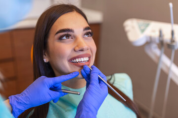 Young female dentist curing patient's teeth filling cavity. Stomatologist working with professional...