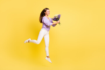 Fototapeta na wymiar Full length body size view of lovely cheerful thin girl jumping walking carrying flowers isolated over bright yellow color background