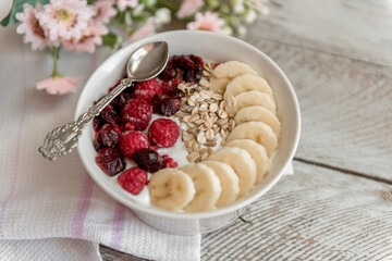 Yogurt bowl with sliced bananas, raspberry and cranberry fruits. Oatmeal with fruits.