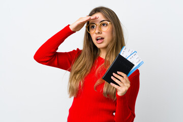 Naklejka premium Young woman over isolated white background in vacation with passport and plane tickets while looking something in the distance