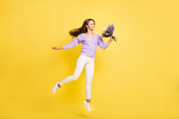 Fototapeta na wymiar Full length body size view of lovely cheerful fit girl jumping smelling flowers isolated over bright yellow color background