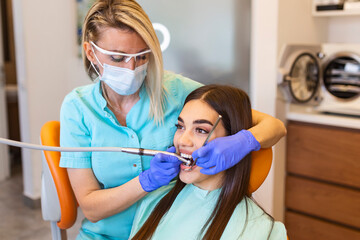 The woman came to see the dentist. She sits in the dental chair. The dentist bent over her. Happy...