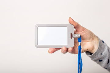 Female hand holds badge, name tag, name tag identifier, lanyard on light background.