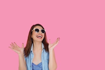 Surprised young woman over pink background.