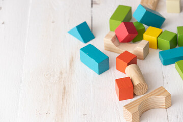 Colorful wooden toy blocks on white wooden table background. Natural materials. Healthy childhood....