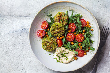 Falafel salad with tomatoes, hummus  and pea sprouts in gray bowl. Plant based food concept.