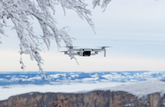 Flying mini drone in action on the winter snow landscape background. Image with selective focus on drone 