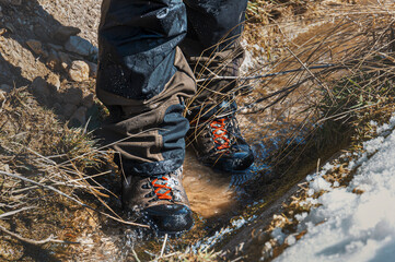 Waterproof boots for hiking, shoes in the water. Detail of men's climbing boots walking through...