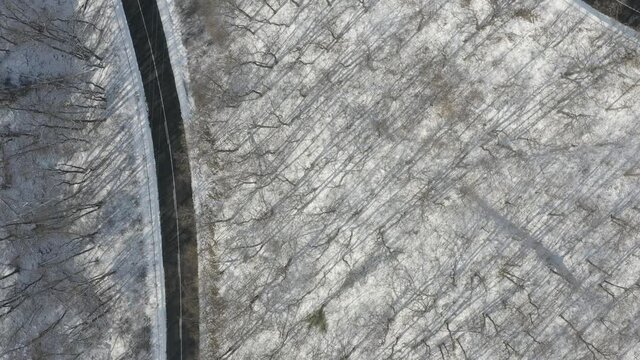 Snowy winter serpentines forest with little traffic on the road on the hill.