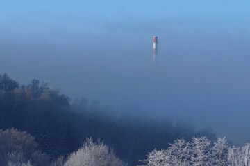 
the factory chimney peeks out of the fog