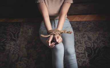 Hands of a victim woman tied with rope.