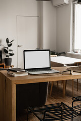 Fototapeta na wymiar Laptop with blank copy space screen on table with notebooks on wooden table. Minimalist home office workspace. Mockup template.