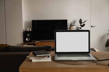 Laptop with blank copy space screen on table with notebooks on wooden table. Minimalist home office workspace. Mockup template.