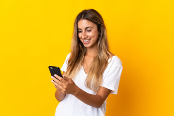 Young hispanic woman over isolated yellow background sending a message or email with the mobile