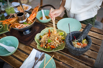Woman having a meal with Pad see ew noodles in a Thai restaurant