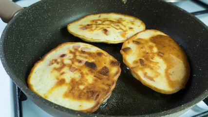 Frying  pancakes in the frying pan.
pancake with sausage in a pan