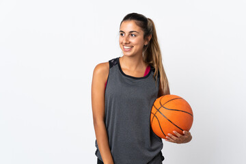 Obraz premium Young hispanic woman playing basketball over isolated white background looking to the side and smiling