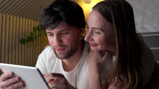 Young couple using tablet on bed in bedroom late at night