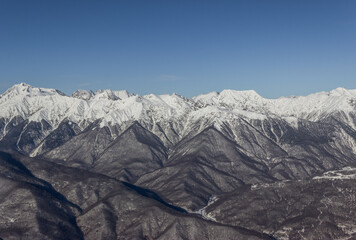 Mountain peaks covered with snow. Winter snow-covered forest in the mountains. Winter landscape. Beautiful blue sky..